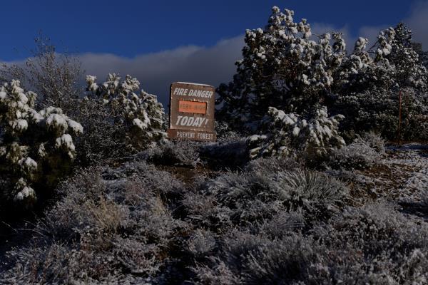 Fresh snow is shown on a fire danger sign near the side of a mountain highway near Taylor, California