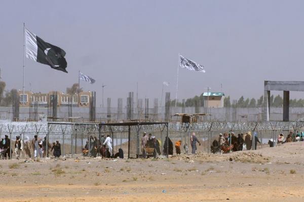 FILE - Pakistan and Taliban flags flutter on their respective sides while people walk through a security barrier to cross border at a key border crossing point between Pakistan and Afghanistan, in Chaman, Pakistan, Aug. 18, 2021. The Taliban win in Afghanistan gave a boost to militants in neighboring Pakistan. Faced with rising violence, Pakistan is taking a tougher line to pressure Afghanistan��s Taliban rulers to crack down on militants hiding on their soil, but so far the Taliban remain reluctant to take action -- trying instead to broker a peace. (AP Photo/Jafar Khan, File)