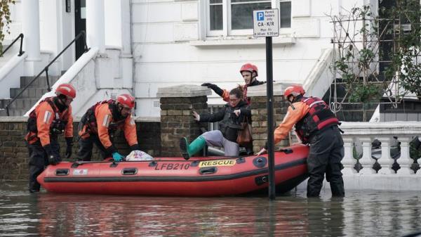 Emergency services help a person on Belsize Road in Camden after a burst water main flooded the London street. London Fire Brigade (LFB) said eight fire engines and around 60 firefighters were called to Belsize Road at 2.50am on Saturday morning after a 42-inch water main burst, causing flooding to a depth of half a metre across an area of around 800 metres. Picture date: Saturday December 17, 2022.

