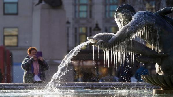 A person takes a picture of a frozen fountain in Trafalgar Square, central London. Snow and ice have swept across parts of the UK, with cold wintry conditions set to continue for days. Picture date: Friday December 16, 2022.