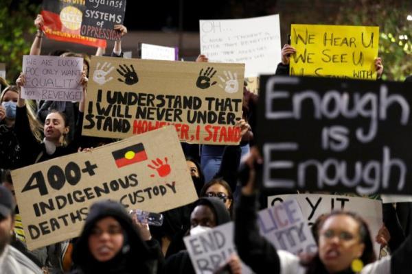 Protestors hold placards that say 